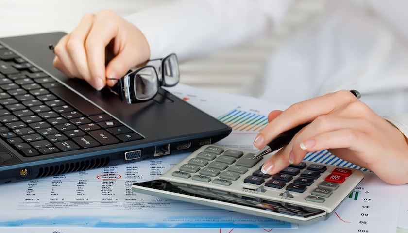 Image of someone doing their accounts using a laptop and calculator, to illustrate an article on Making Tax Digital (MTD)