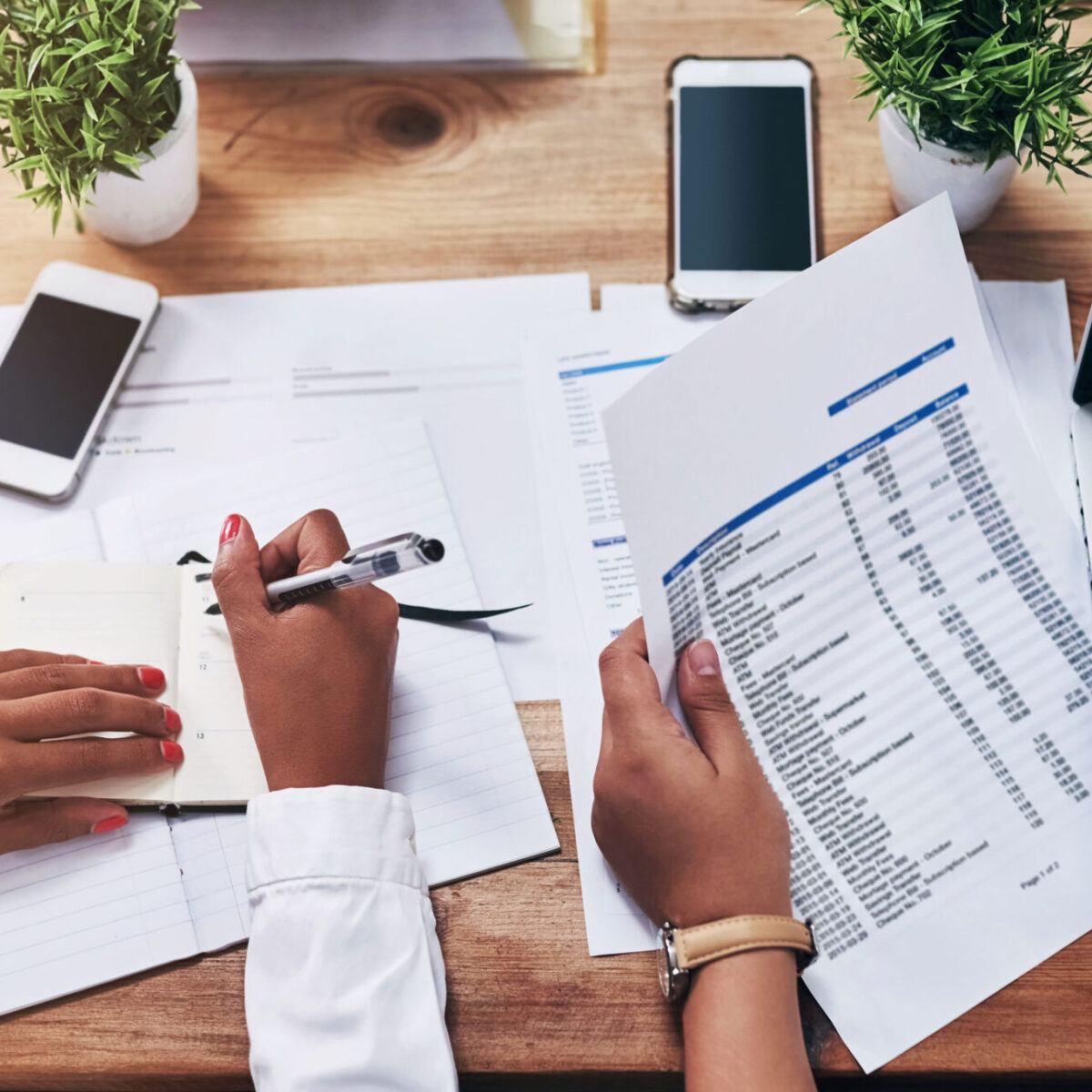 Picture of hands writing on financial paperwork to illustrate an article on 'What does an auditor do?'